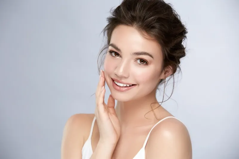 A smiling woman with her hair up, one hand resting on her cheek